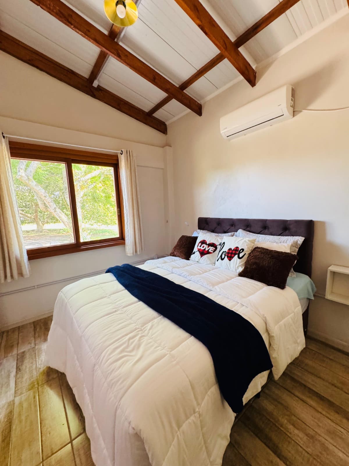 Quarto de casal com teto de madeira e vista para o jardim